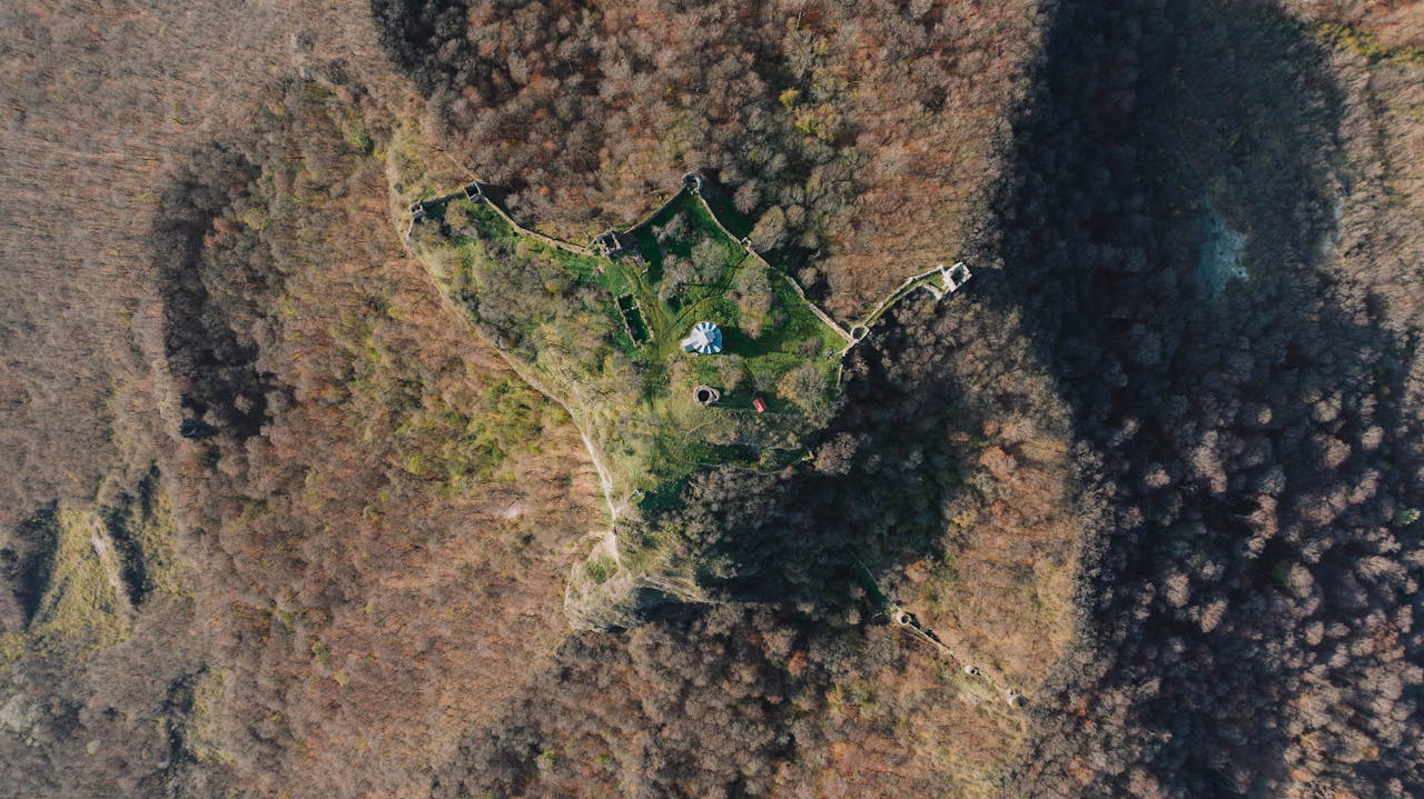 Aerial drone shot of Bochorma Fortress surrounded by fall foliage in Georgia's Mtskheta-Mtianeti region.