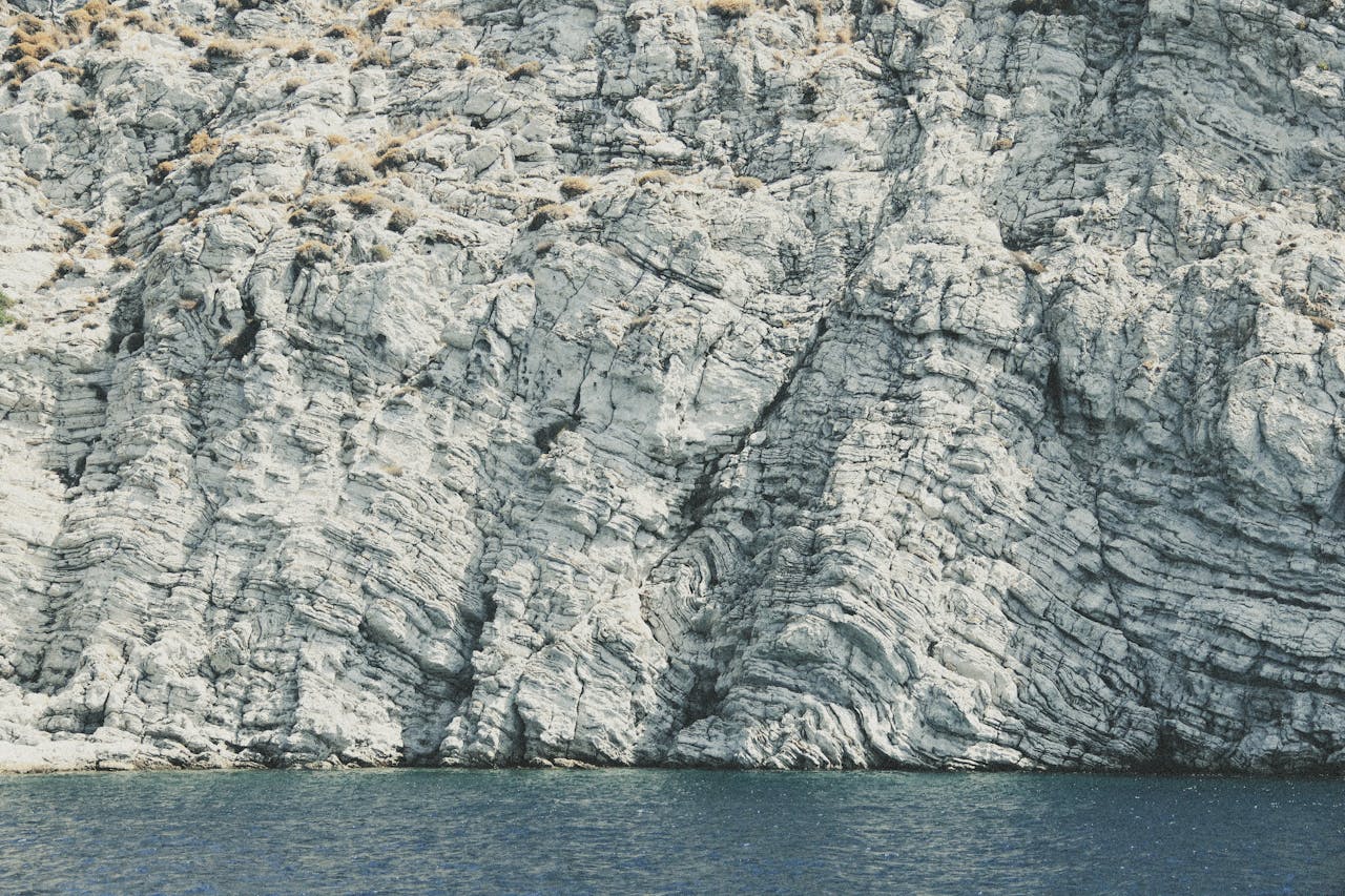 Stunning view of a textured cliff meeting the blue waters near Marmaris, Türkiye.